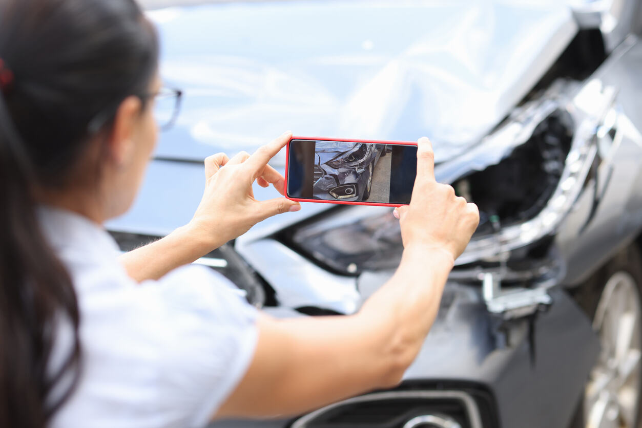 A person documenting car damage with a smartphone, illustrating steps involved in calculating damages in a Colorado wrongful death claim.
